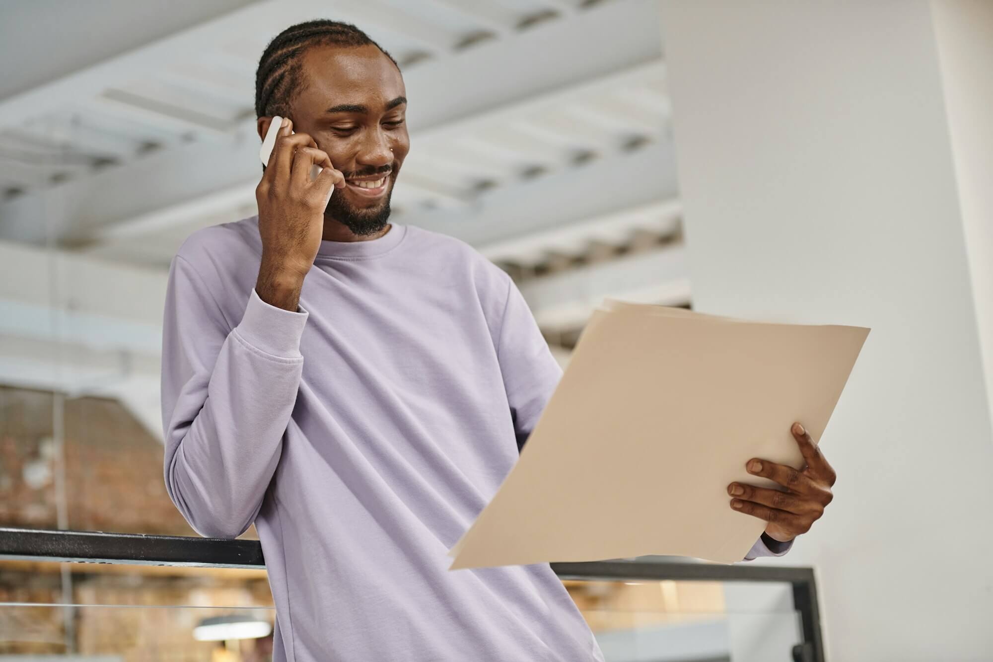 happy-african-american-man-looking-at-project-on-paper-talking-on-smartphone-planning-startup.jpg